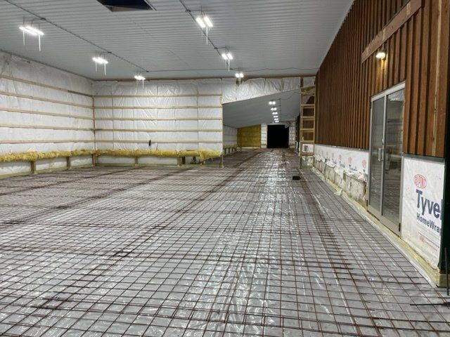 A large empty room with a concrete floor and a wooden wall.