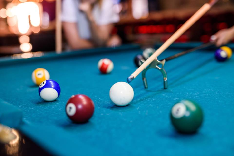 Tavolo da biliardo con palline di vari colori; stecca e bridge in uso.