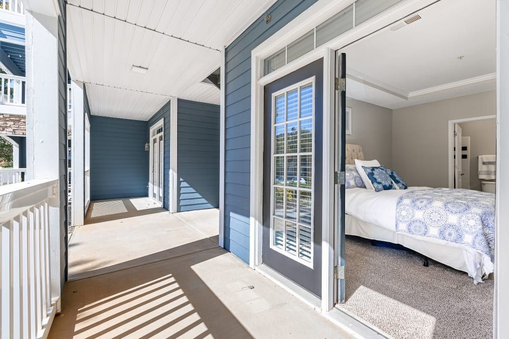 a bedroom with a bed and a balcony with sliding glass doors at Marquis on Edwards Mill in Raleigh, NC. 