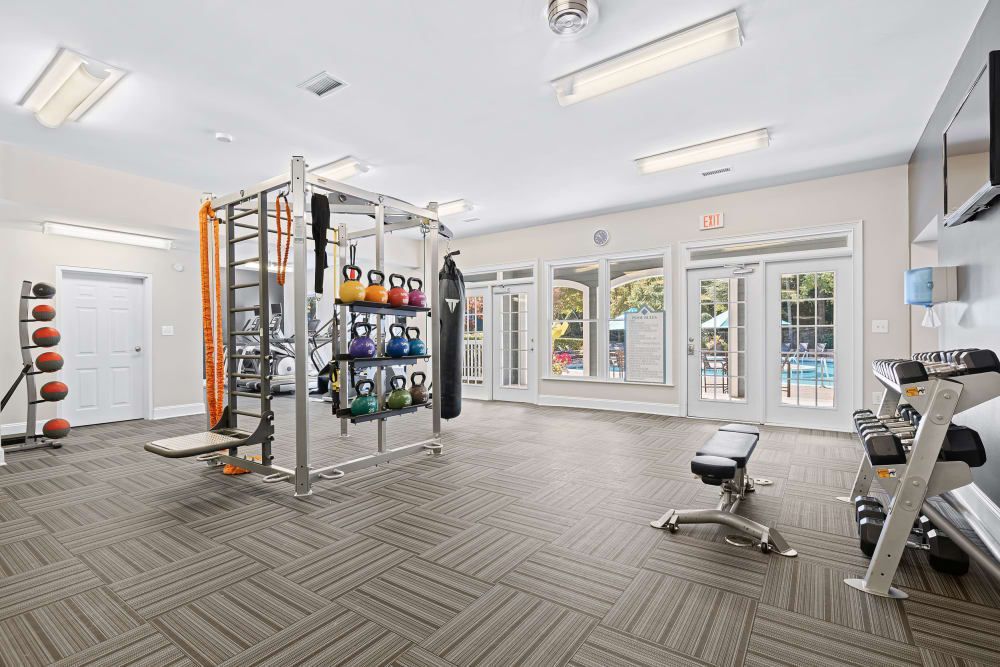 a large gym with a lot of equipment and a pool in the background at Marquis on Edwards Mill in Raleigh, NC. 