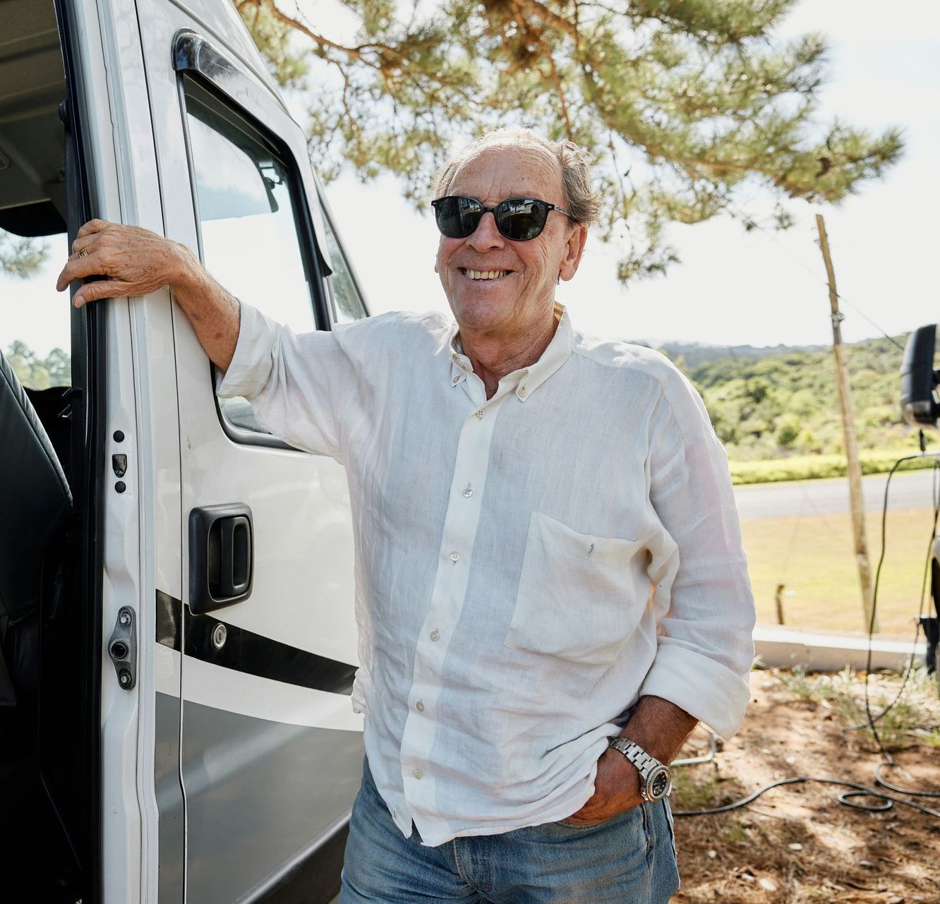 A man wearing sunglasses is leaning against a white van