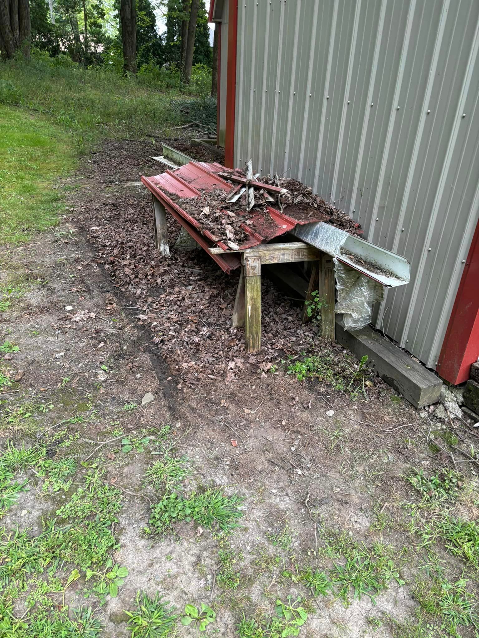 A red wheelbarrow filled with leaves is sitting next to a shed.
