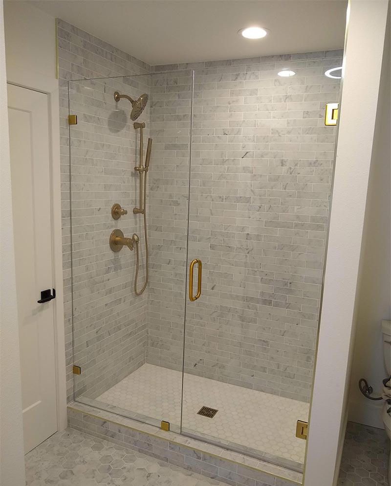 Frameless glass shower door with gold hardware installed by A1 Handyman in Boise, ID.