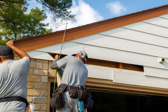 Contractors repairing exterior house siding above a garage on a Boise, Idaho home.”