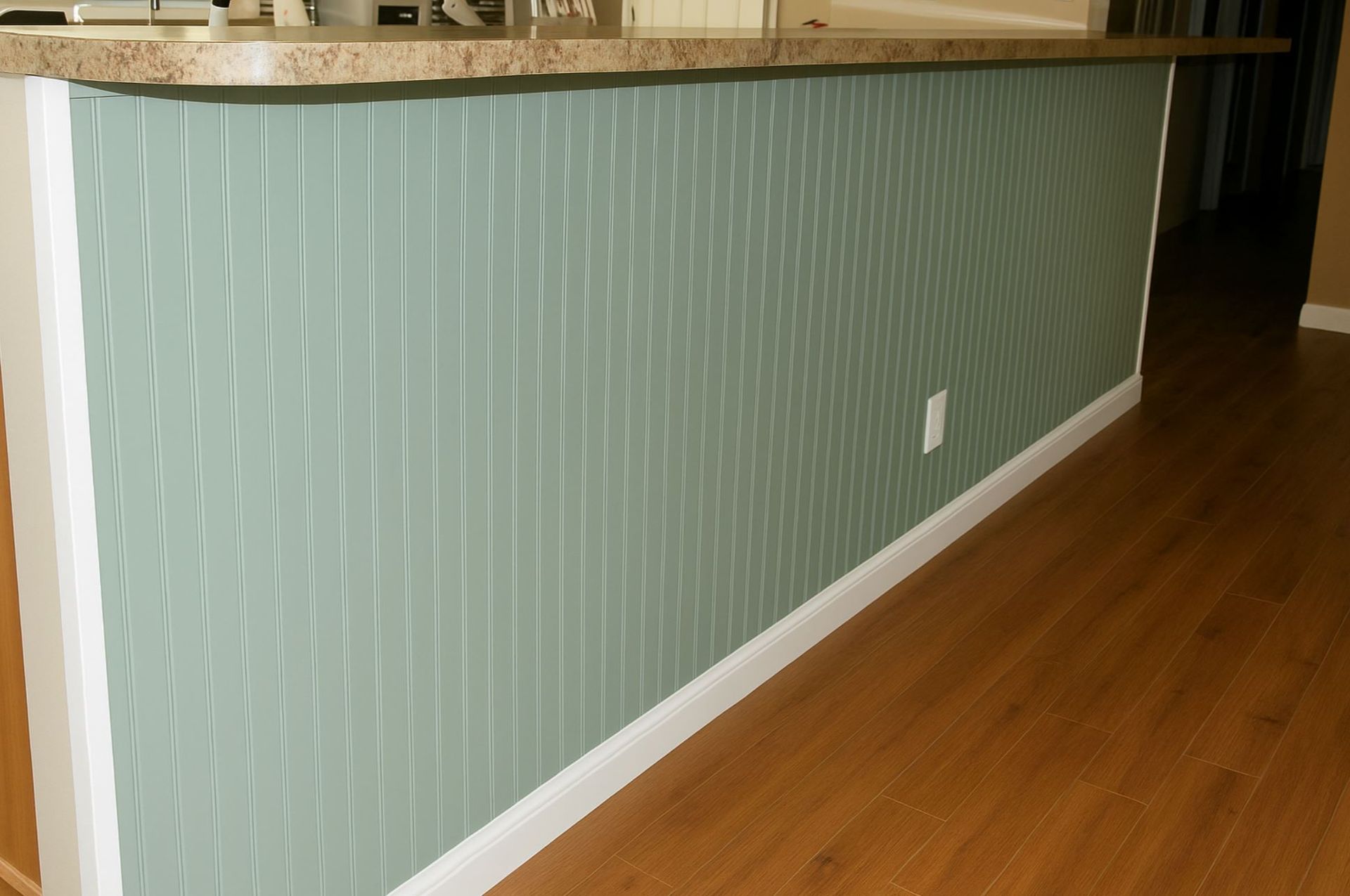 Interior view of a kitchen half-wall featuring green vertical beadboard paneling installed by A1 Handyman, with white trim