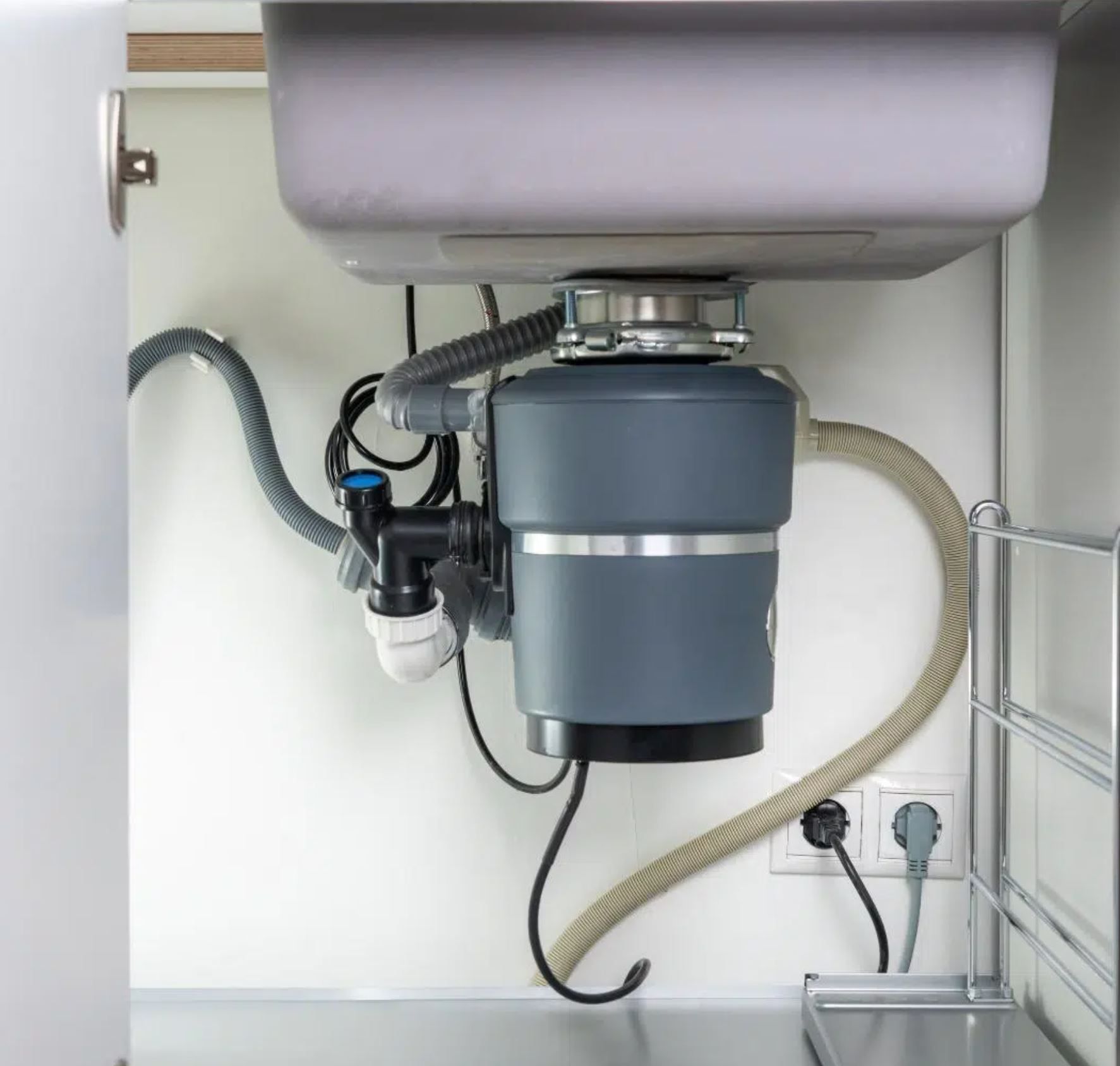 Garbage disposal installed under a kitchen sink with properly connected drain and power