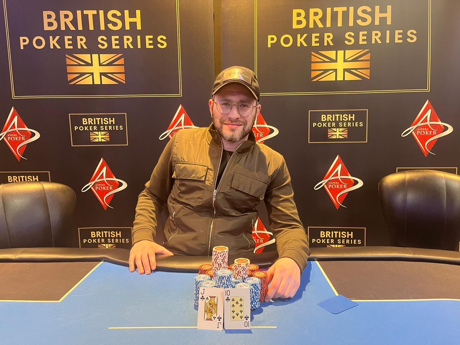 Man at poker table with chip stacks and British Poker Series banner.