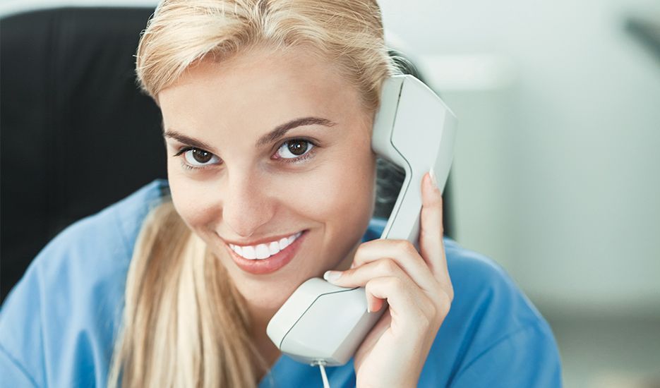 A woman is smiling while talking on a phone