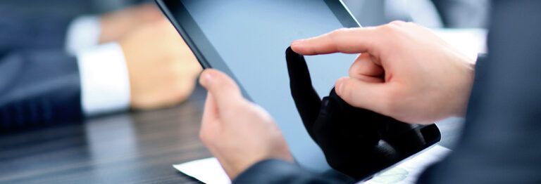 A man in a suit is using a tablet computer.