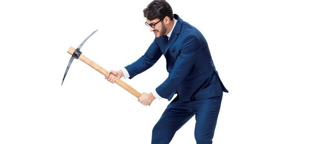 A man in a suit is holding a pickaxe.