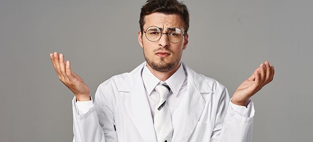 A man in a lab coat and tie is shrugging his shoulders.