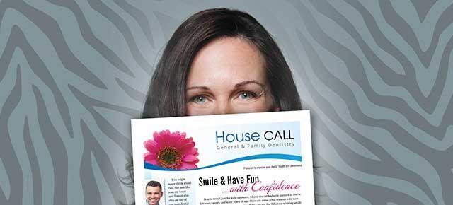 A woman is holding a house call flyer in front of her face.