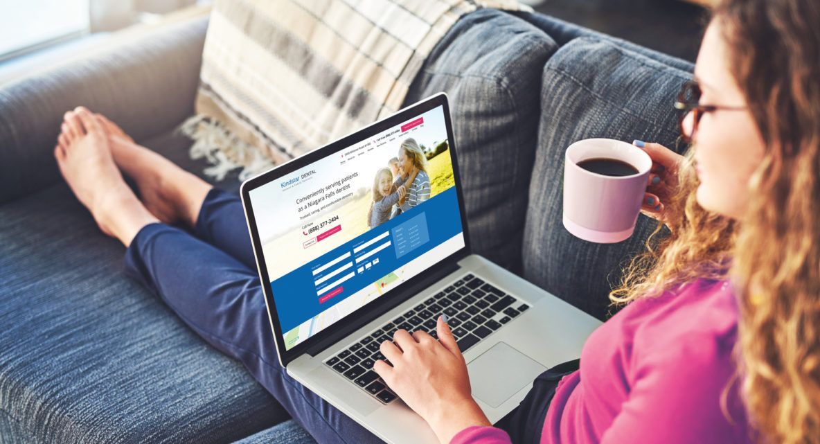 A woman is sitting on a couch using a laptop computer.