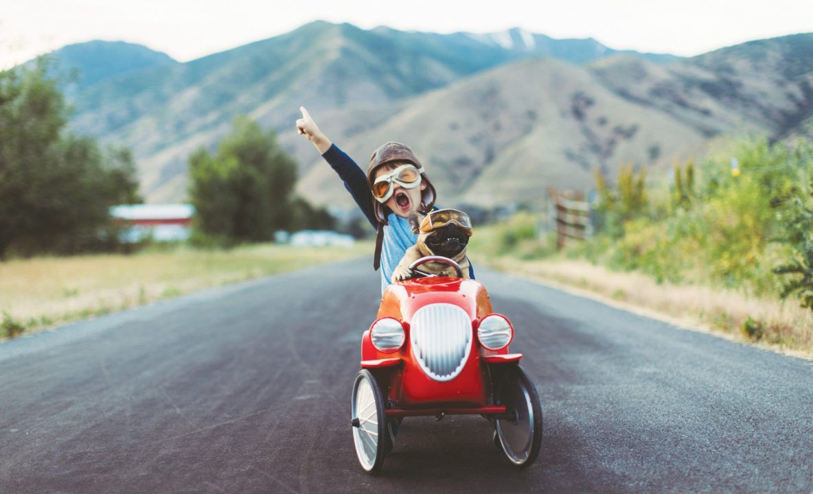 A little boy is driving a toy car down a road.