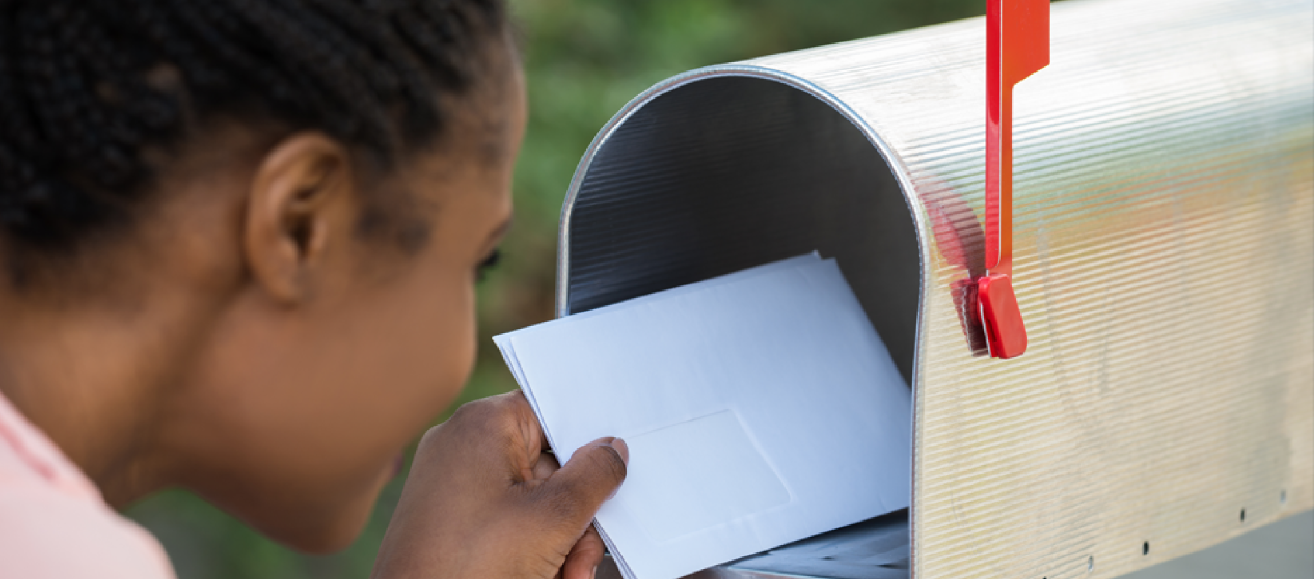 A woman is putting a letter in a mailbox.