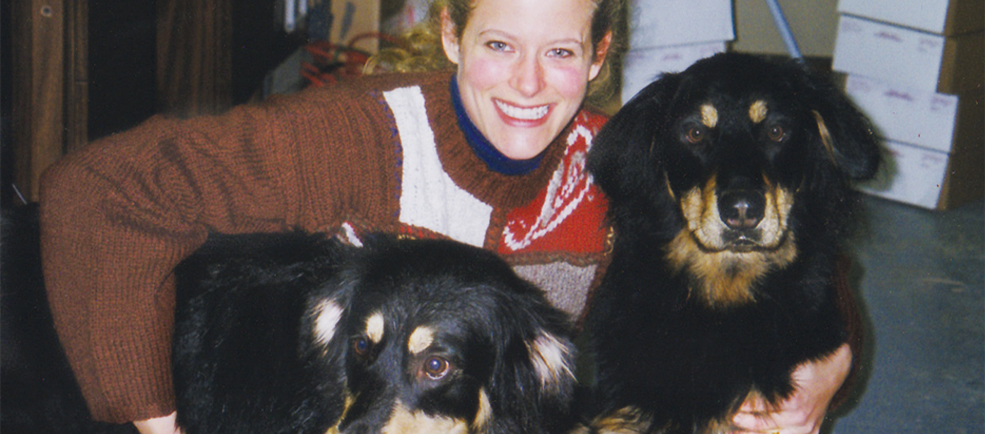 A woman is posing for a picture with two dogs.