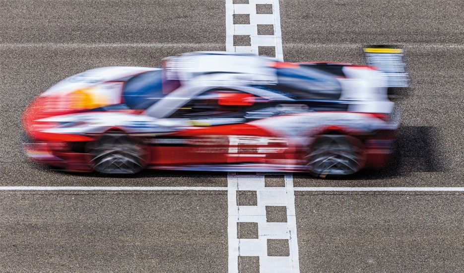A red and white race car is driving down a track.