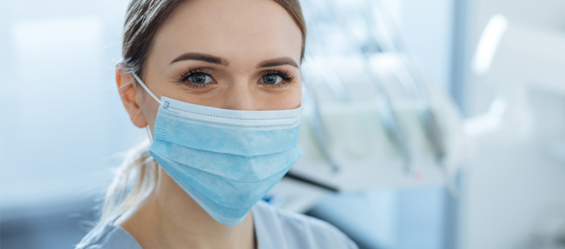 A close up of a woman wearing a surgical mask.