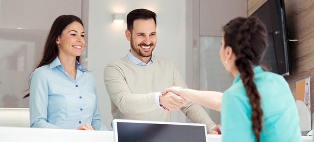 A man and a woman are shaking hands with a nurse at a dental office.