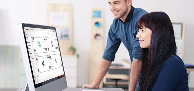 A man and a woman are looking at a computer screen.