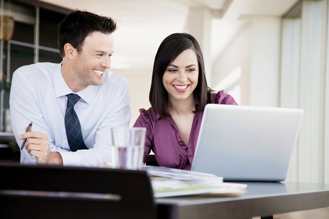 A man and a woman are looking at a laptop computer.