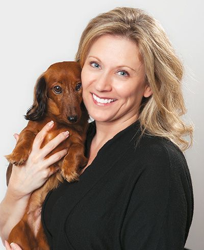 A woman in a black shirt is holding a brown dog