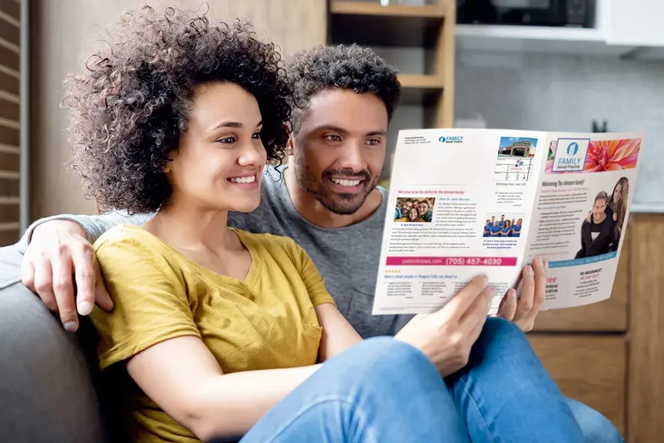 Couple reading a dental direct mail newsletter promoting local dental services.