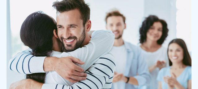 A man is hugging a woman in front of a group of people.