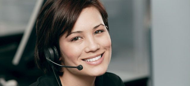 A woman wearing a headset is smiling and looking at the camera.