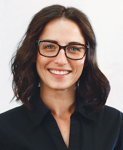 A woman wearing glasses and a black shirt is smiling.
