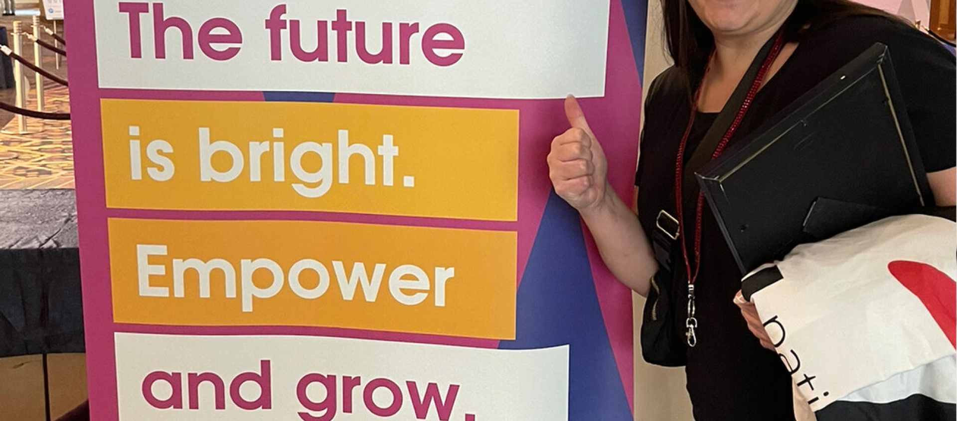 A woman is standing in front of a sign that says `` the future is bright , empower and grow ''.