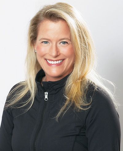 A woman wearing a black jacket is smiling for the camera.
