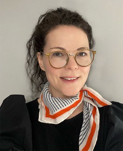 A woman wearing glasses and a scarf around her neck.