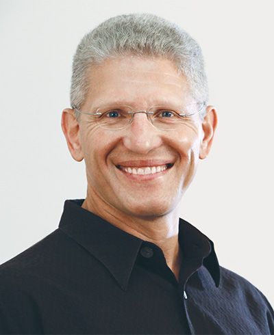 A man wearing glasses and a black shirt smiles for the camera