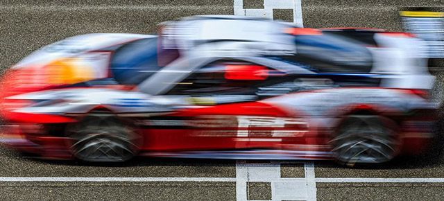 A red and white race car is driving down a track.