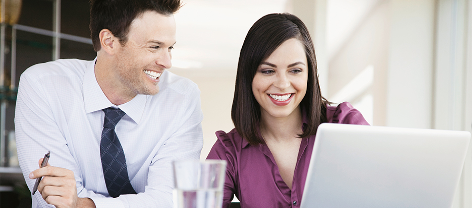 A man and a woman are looking at a laptop computer.