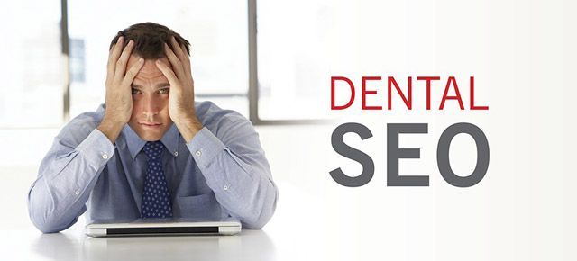 A man is sitting in front of a laptop computer with his hands on his head.