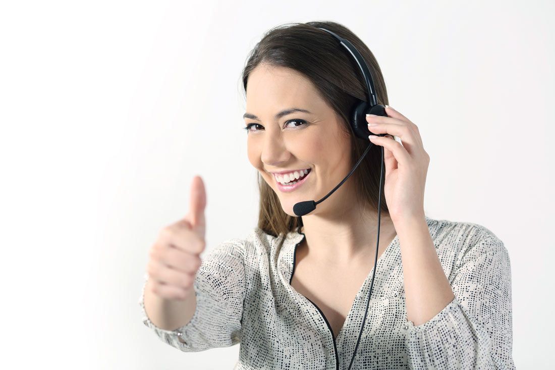 A woman wearing a headset is giving a thumbs up.