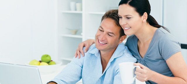 A man and a woman are looking at a laptop together.