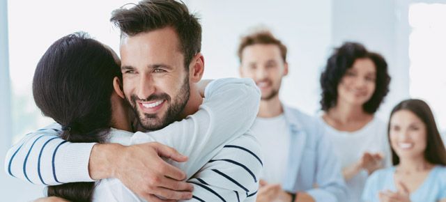 A man is hugging a woman in front of a group of people.