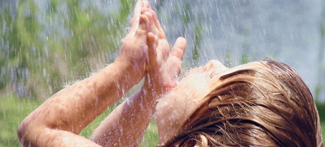 A woman is taking a shower outside in the rain.