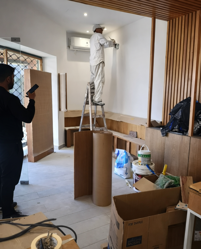 Un trabajador subido a una escalera pinta una pared de blanco