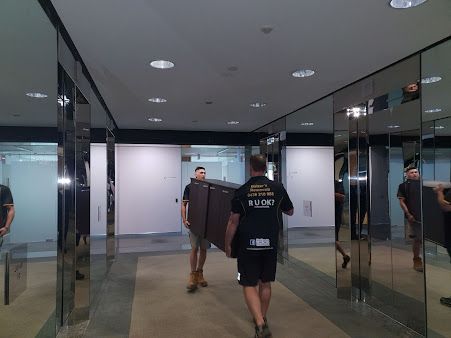 Two Men Are Carrying A Large Piece Of Furniture Down A Hallway — Balzers Removals and Carrying in Helidon, QLD