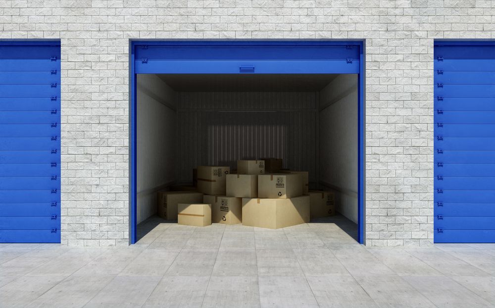 A Stack Of Cardboard Boxes In A Garage With Blue Doors — Balzers Removals and Carrying in Highfields, QLD