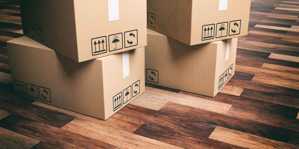 Three Cardboard Boxes Are Stacked On Top Of Each Other On A Wooden Floor — Balzers Removals and Carrying in Gatton, QLD