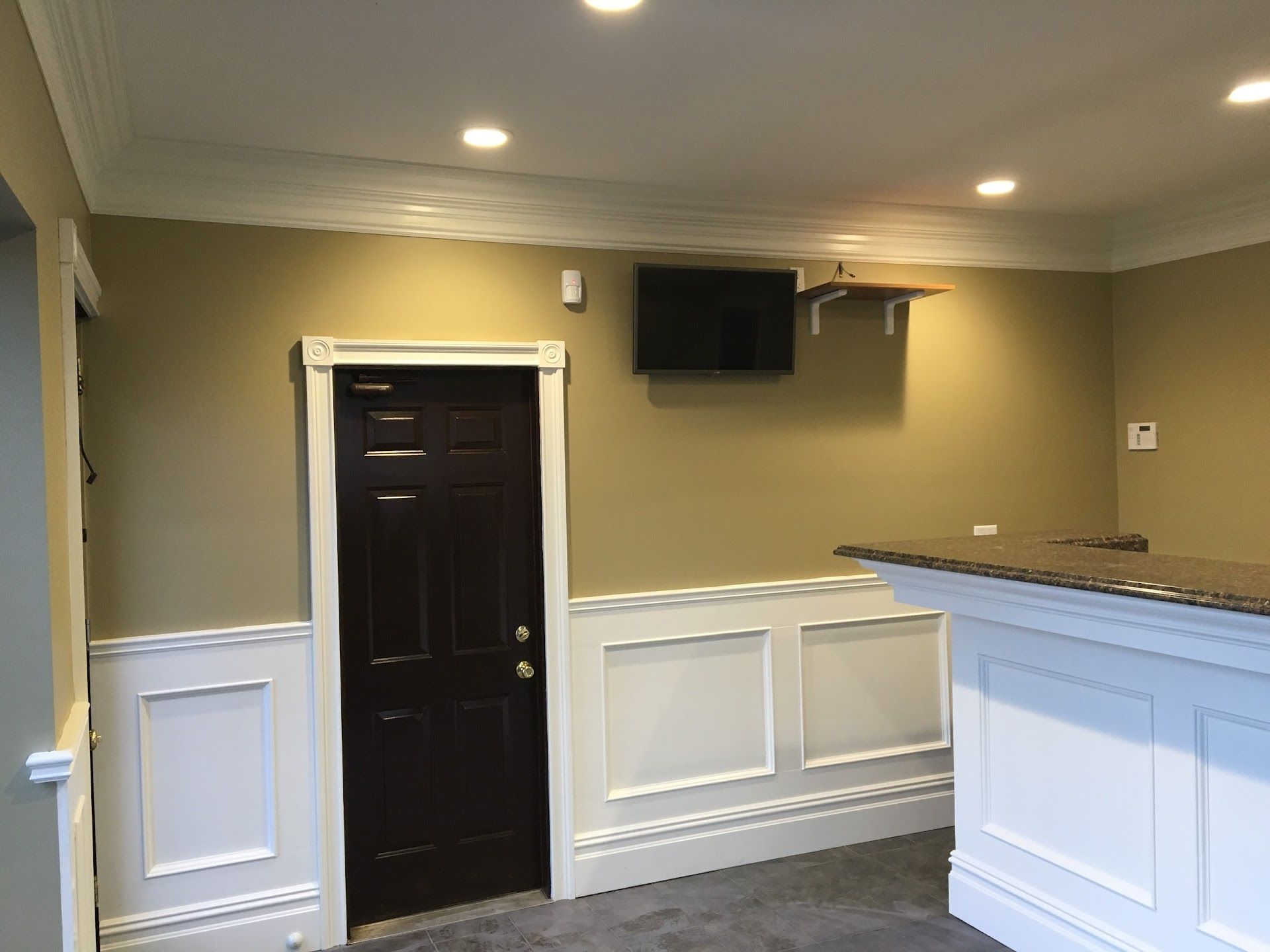 Interior with brown door, TV, white wainscoting and trim, and tan walls. | D & D Auto Clinic