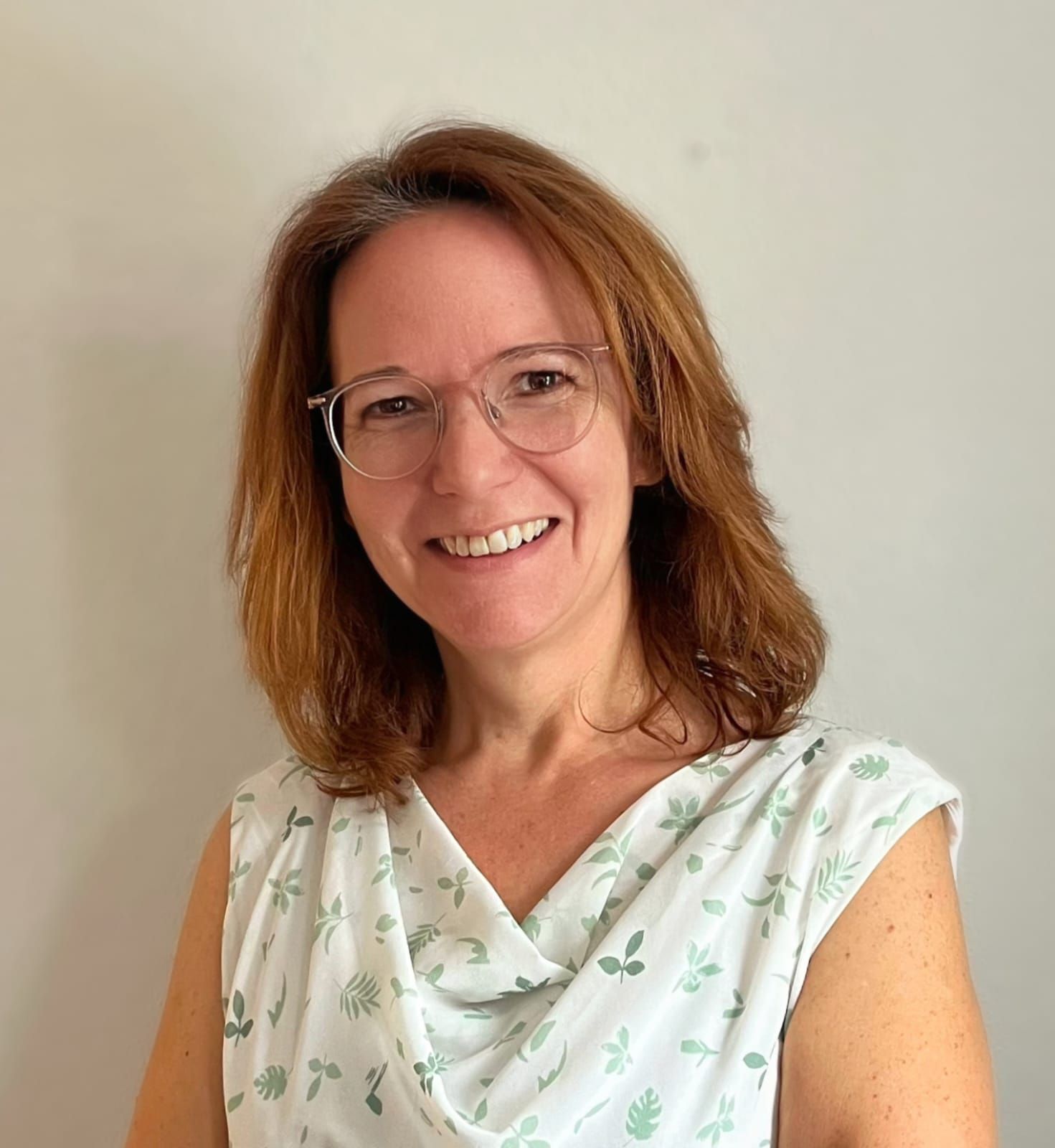 Sonja Weinberger Porträt Sonja Weinberger, freundlich lächelnde Frau mit Brille, Schulterlanges hellbraunes Haar, sommerliches Oberteil
