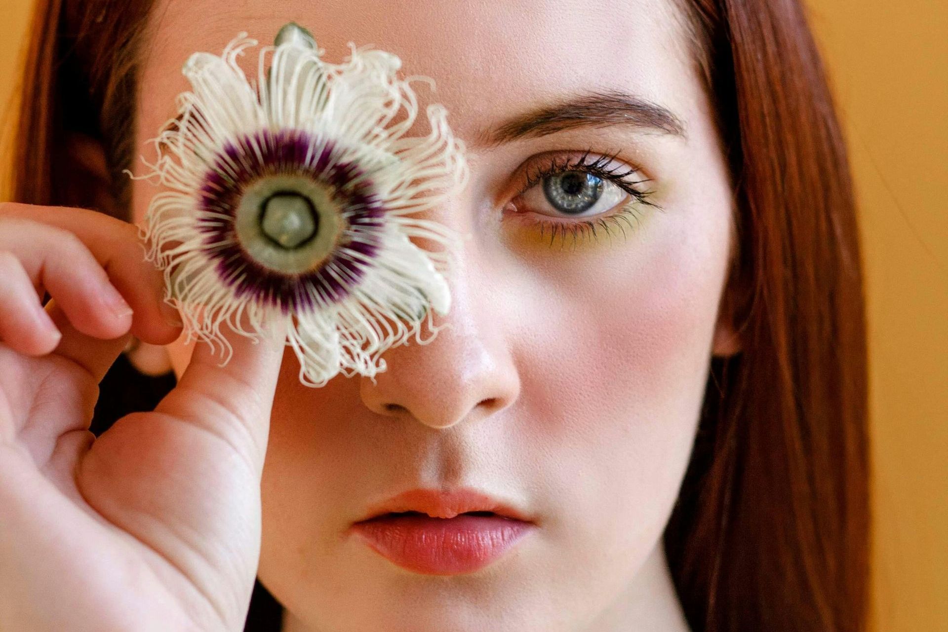 Visualtraining Junge Frau verdeckt ein Auge mit einer Blüte