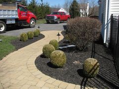 Landscape crew mowing and edging a suburban lawn beside a house on a sunny day