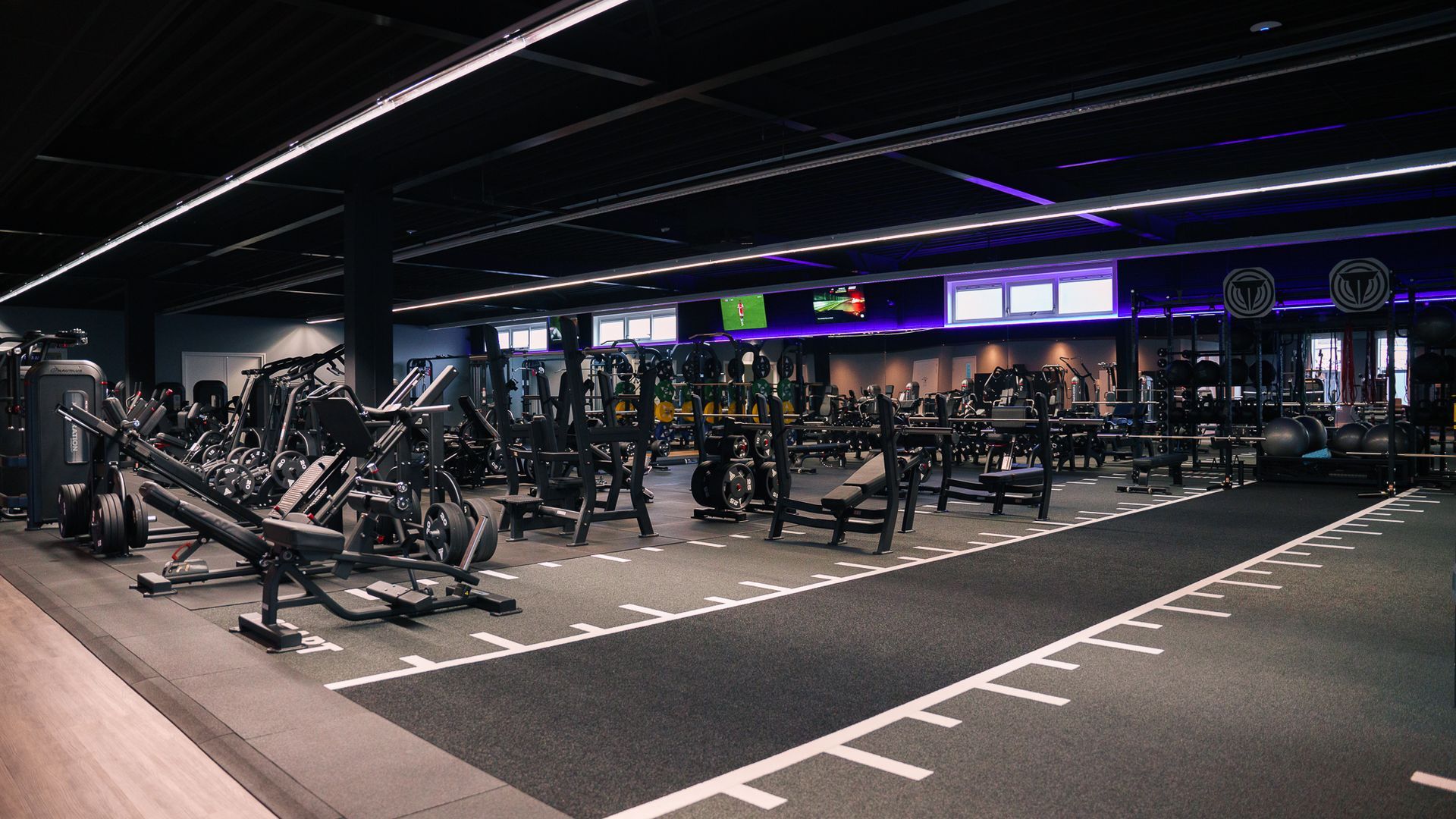 Een sportschool vol met fitnessapparatuur en een atletiekbaan.